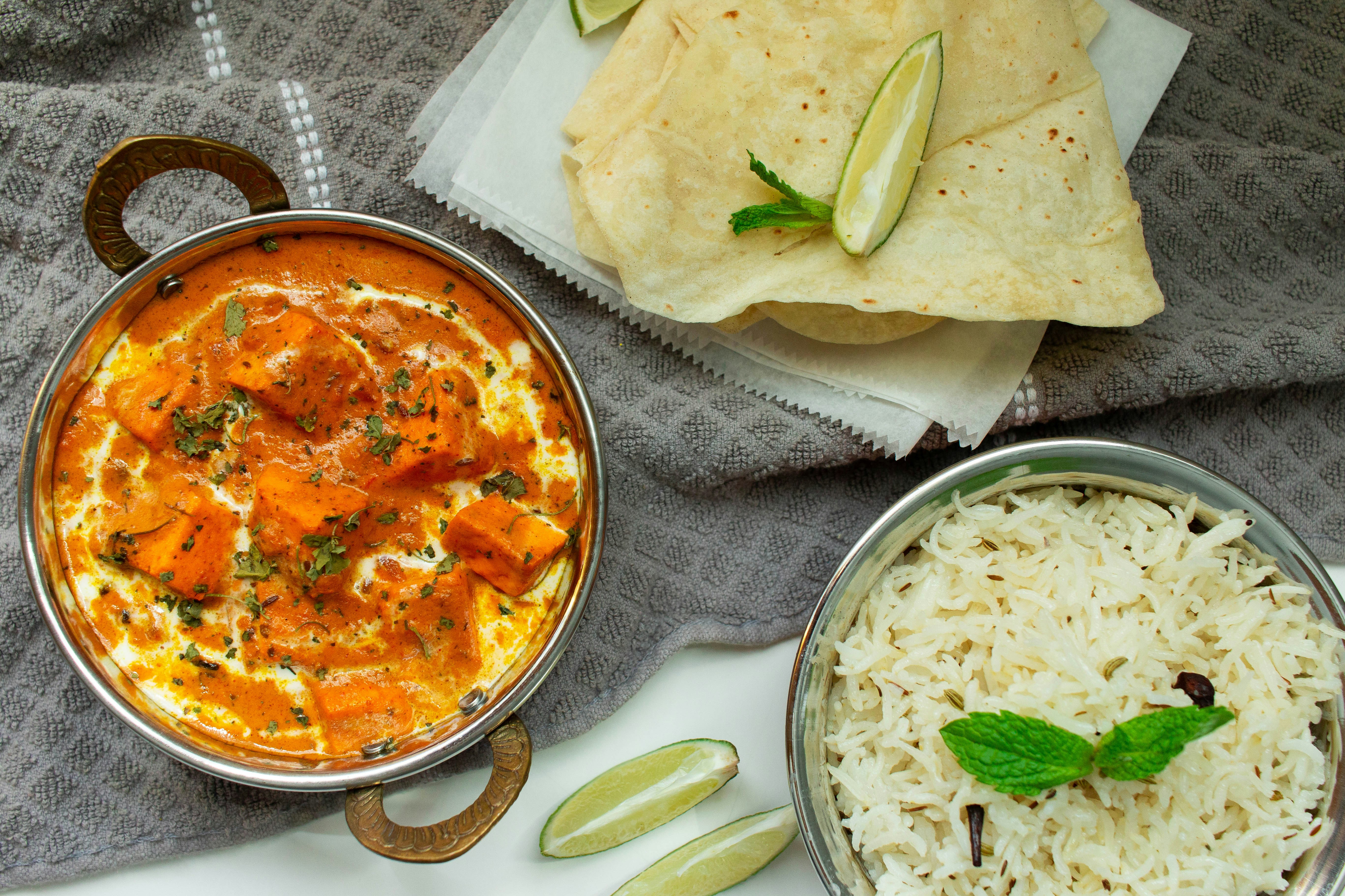 Paneer masala curry in orange gravy served with rotis and rice